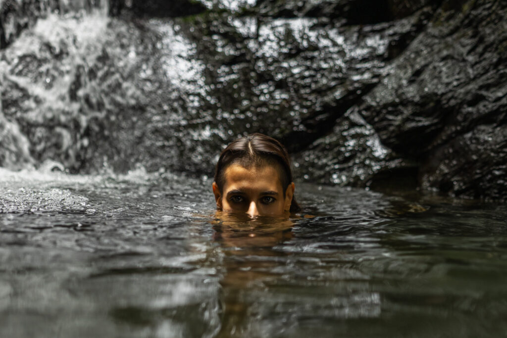ethereal portrait of woman submerged in a waterfall
